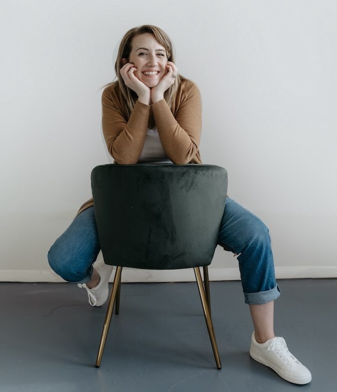 Hayley Rissler from CopyClick Studio sitting backwards on a chair smiling