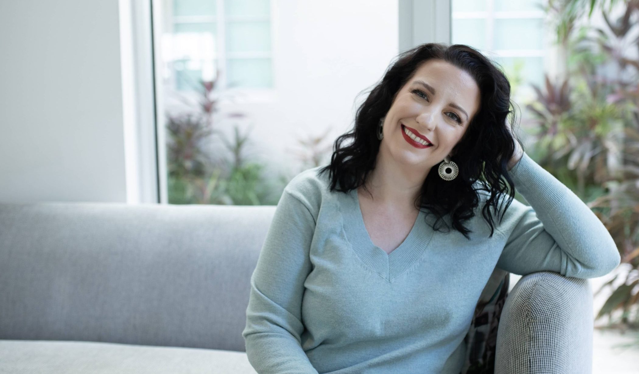 Monica Froese smiling sitting on a couch